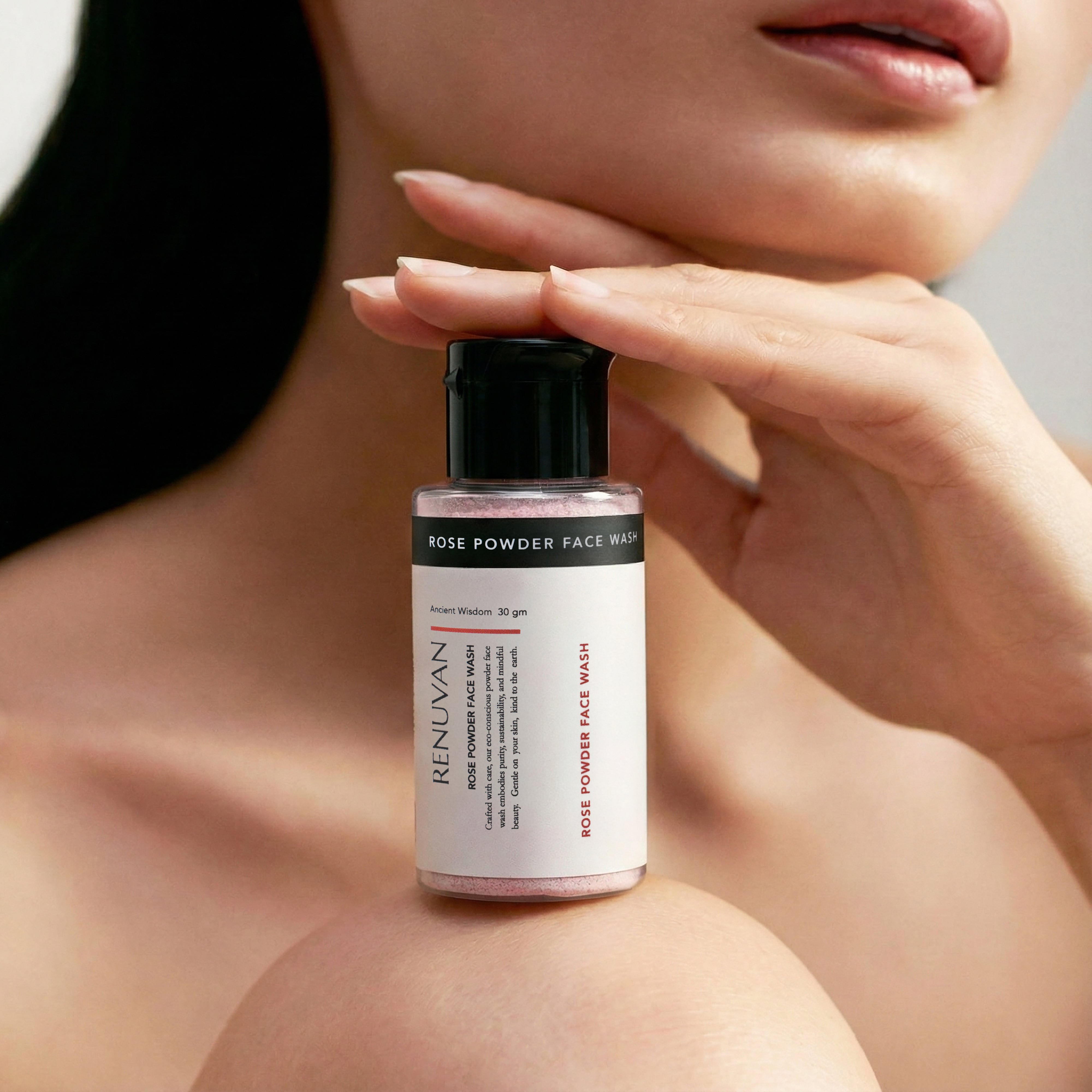 Renuvan Rose Powder Face Wash bottle held by a hand with a blurred background