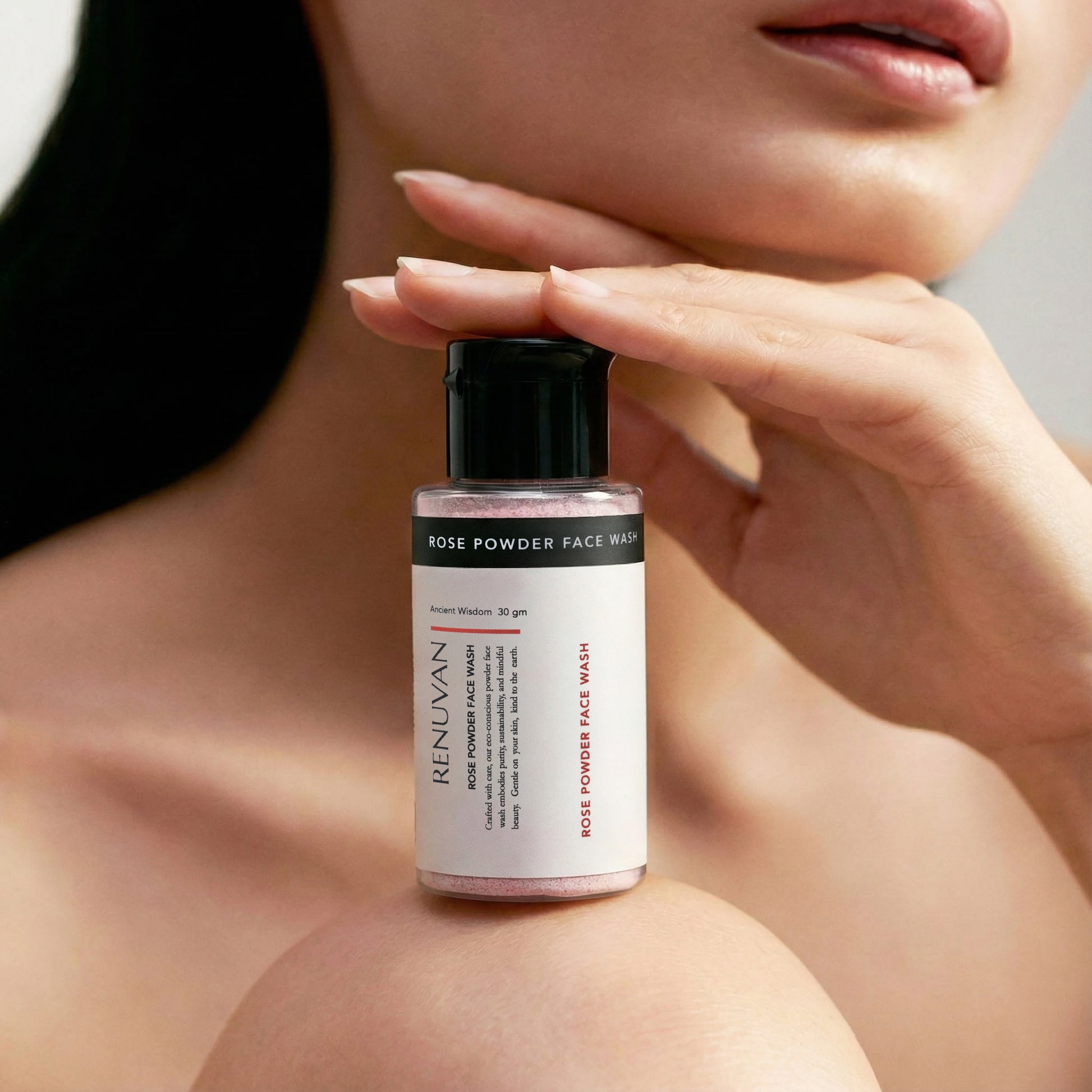 Renuvan Rose Powder Face Wash bottle held by a hand with a blurred background