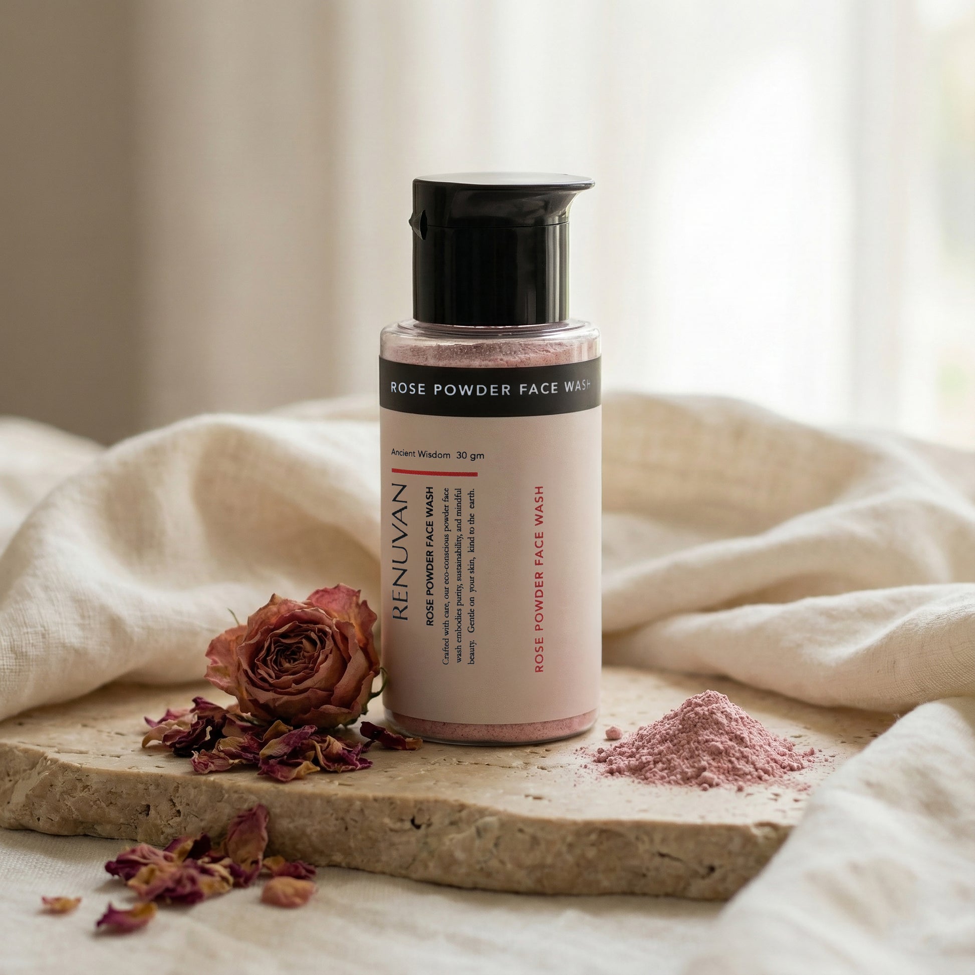 renuvan Rose powder face wash bottle with dried rose on a stone surface