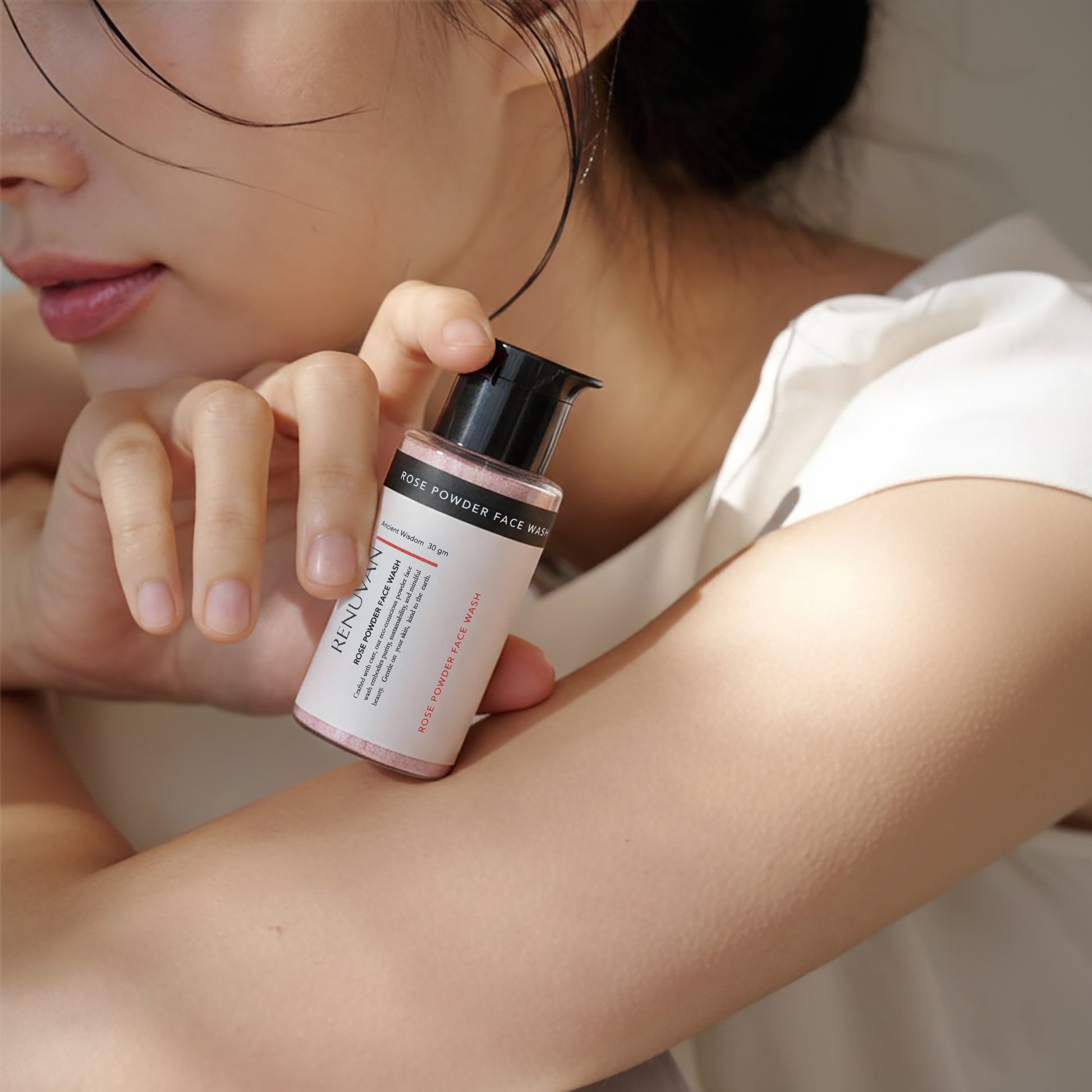 Person holding a skincare product close to their face